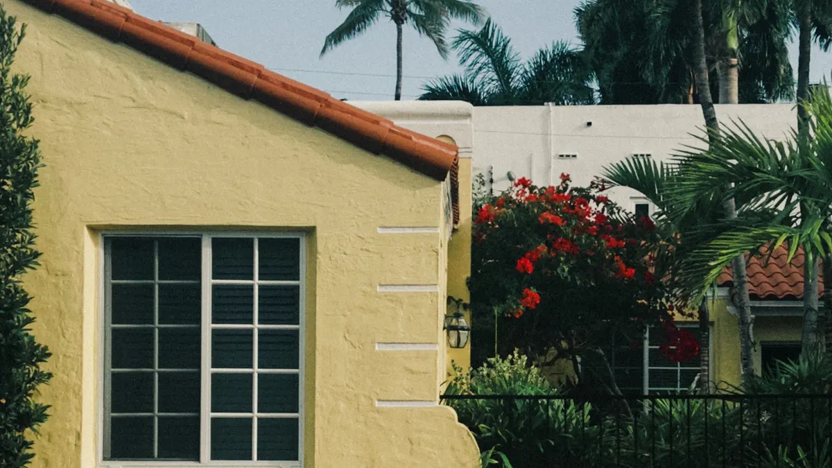 Yellow stucco home with a tile roof and garden wall in Miami